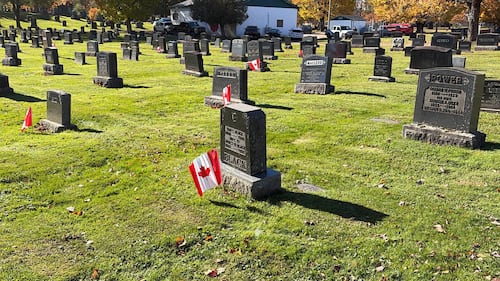 Canadian flags are pictured next to grave stones.
