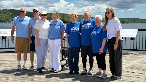 A group of people pose for a photo on a boardwalk.