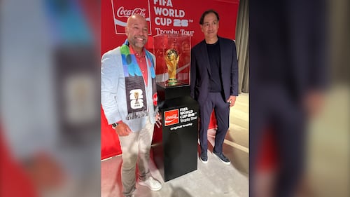 Two men pose with the FIFA World Cup Trophy.