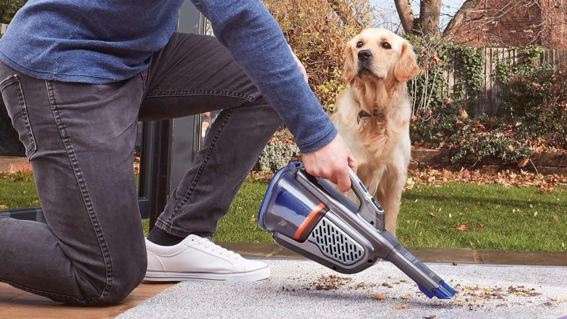 A person vacuuming a carpet with the BLACK+DECKER Dustbuster Handheld Vacuum for Pets.