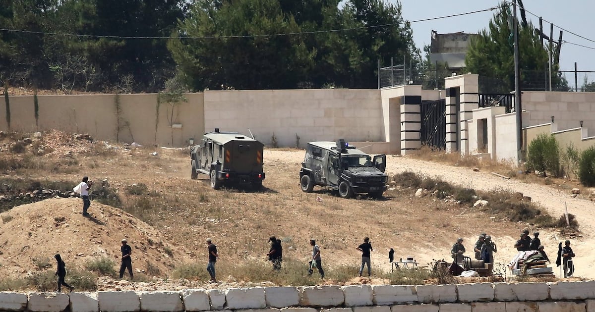 Photo: ctvnews.ca Israeli soldiers stand guard next to settlers in front of Palestinian homes that they have blockaded in the village of