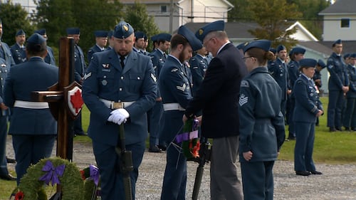 Members of the military stand with their heads bowed.