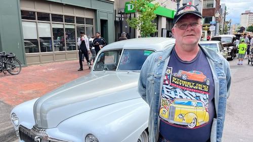 A man poses next to a car for a photo.