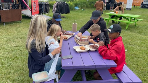 A family sits at a purple picnic table.