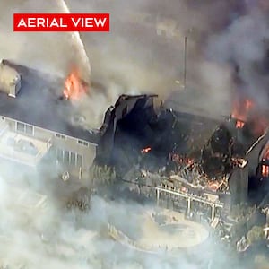 Firefighters spray water on houses engulfed by wildfires in Southern California