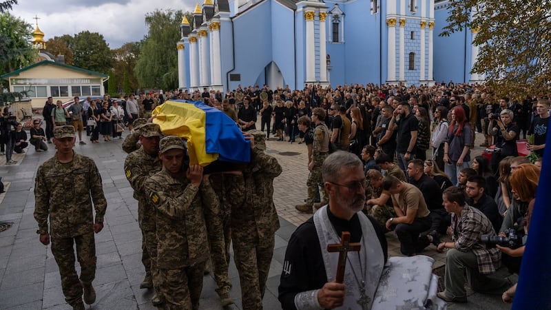 A pregnant soldier mourns her 21-year-old husband at his funeral in Ukraine