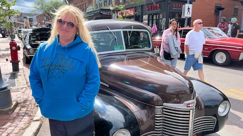A woman poses next to a car for a photo.
