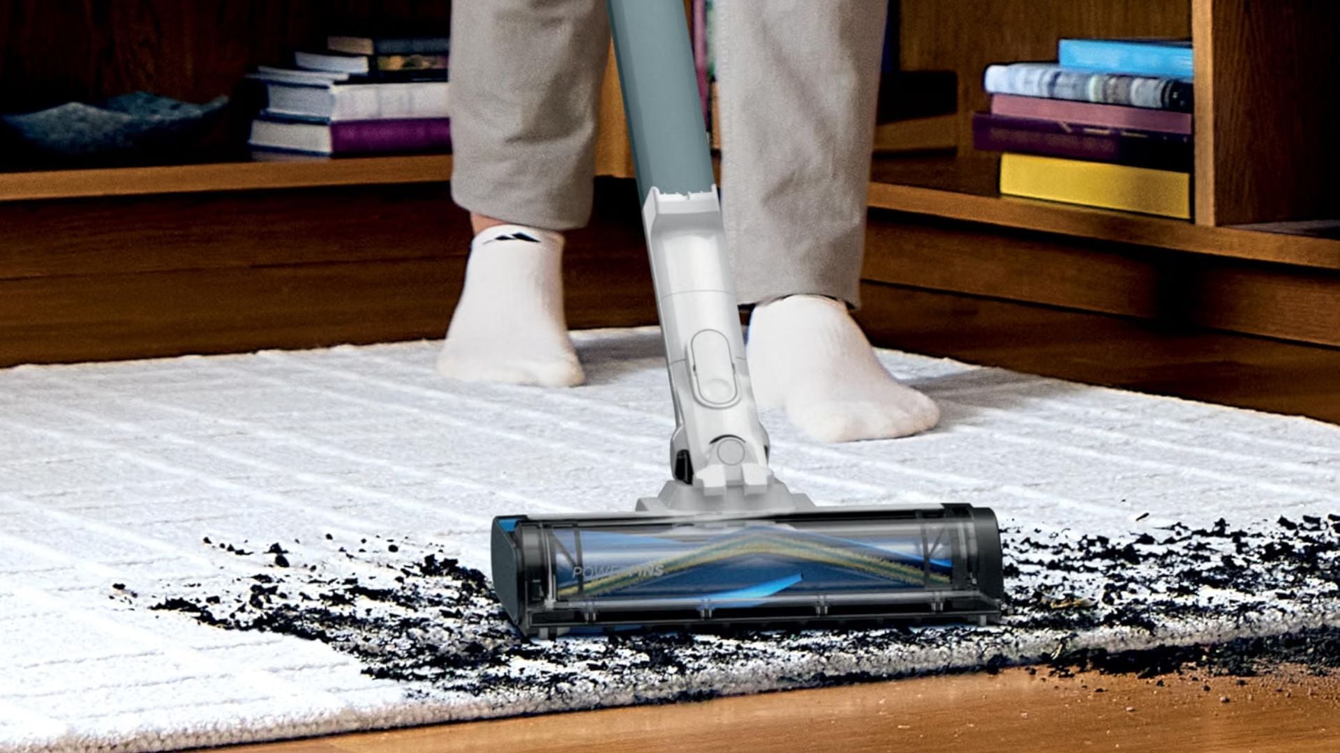 A person cleaning dirt off a carpet with the Shark PowerPro Plus Cordless Stick Vacuum.