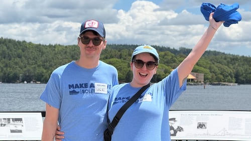 A man and a woman wearing blue t-shirts pose for a photo.