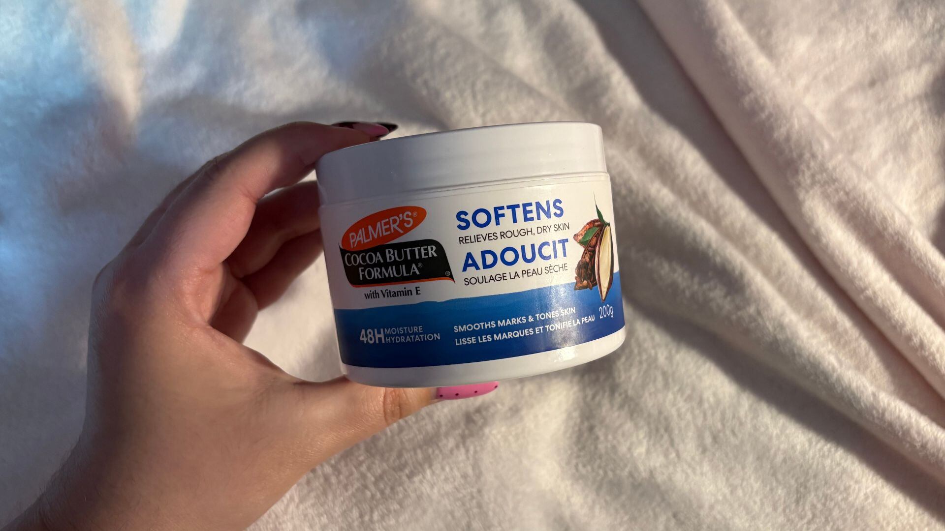 Bianca holding the container of moisturizer with a soft background
