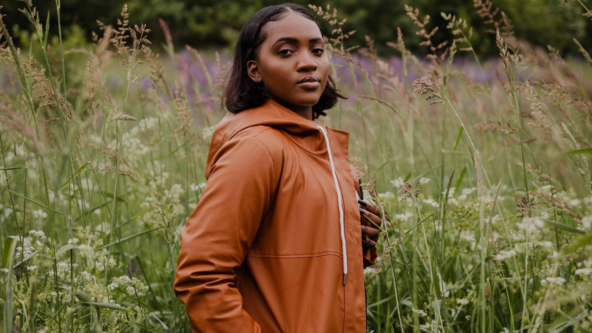 A person in a wildflower field wearing a Mernini rain jacket.