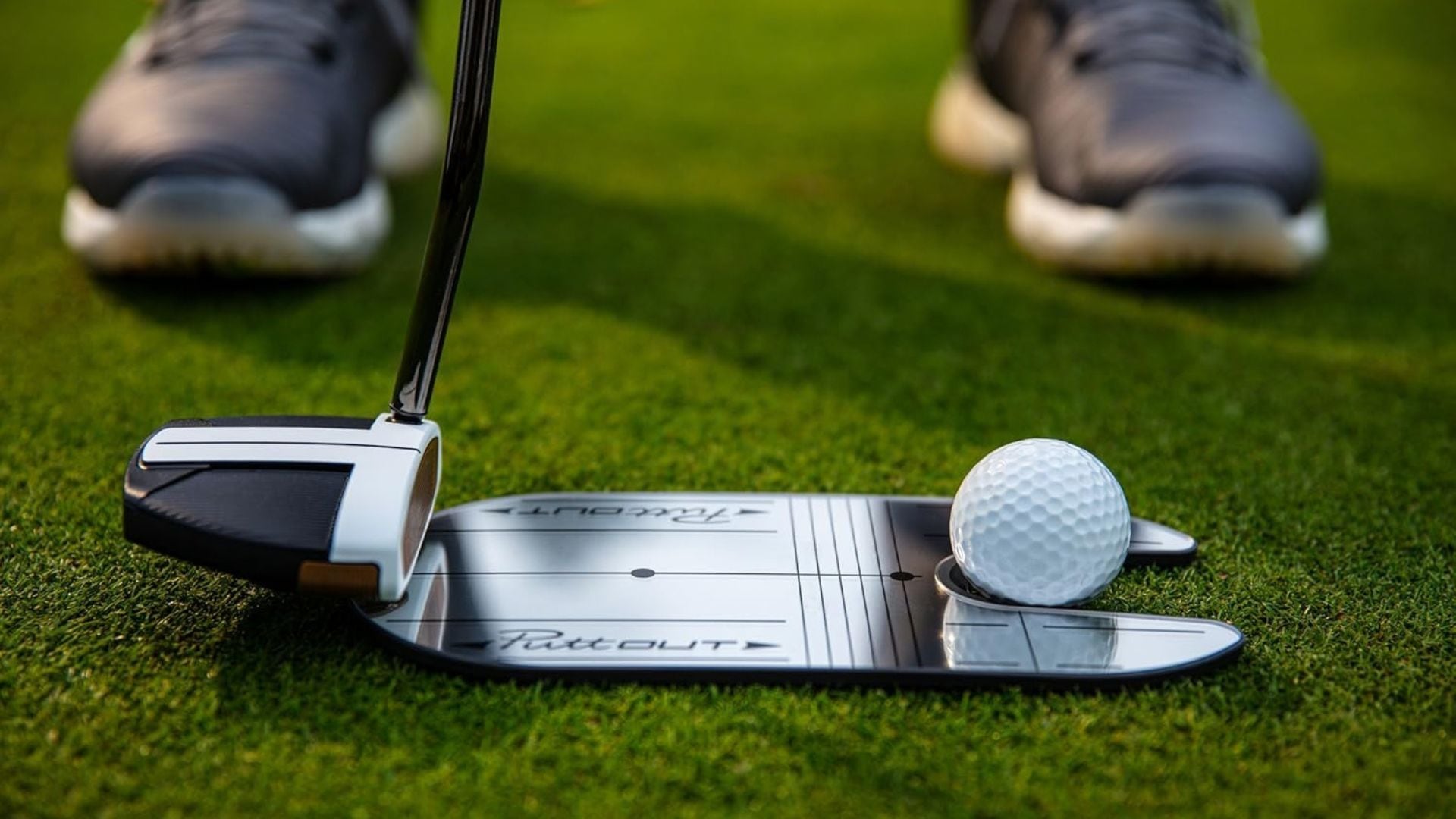 A person using a putting mirror to perfect their golf shot.