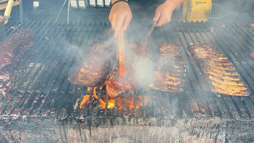 Ribs are cooking on a grill.