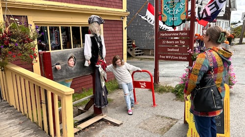 A child takes a picture with a scarecrow.