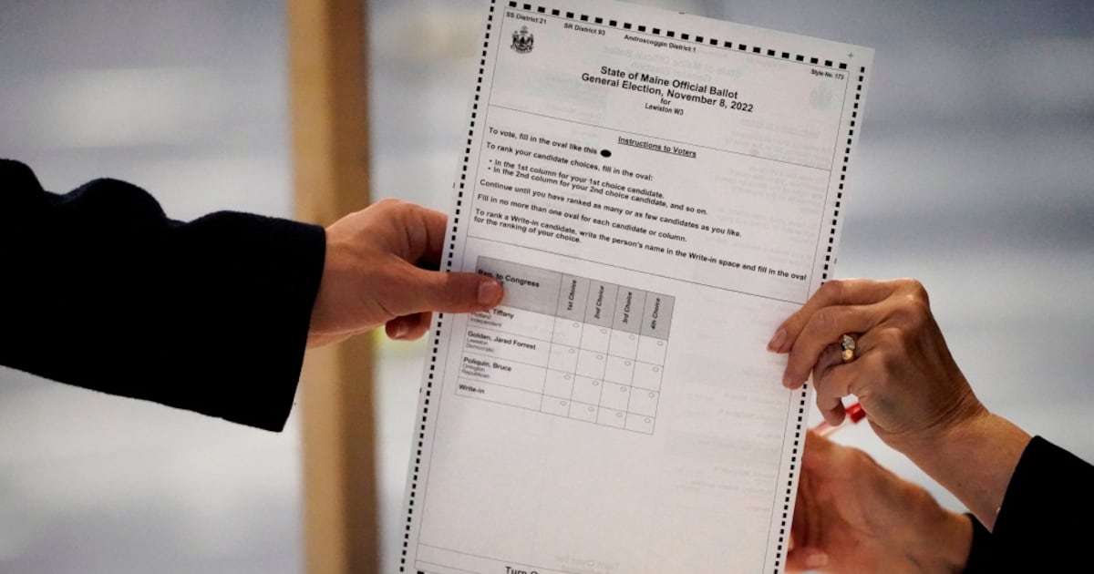 A clerk hands a ballot to a voter on Election Day, Tuesday, Nov. 8, 2022, in Lewiston, Maine. (AP Photo/Robert F. Bukaty)