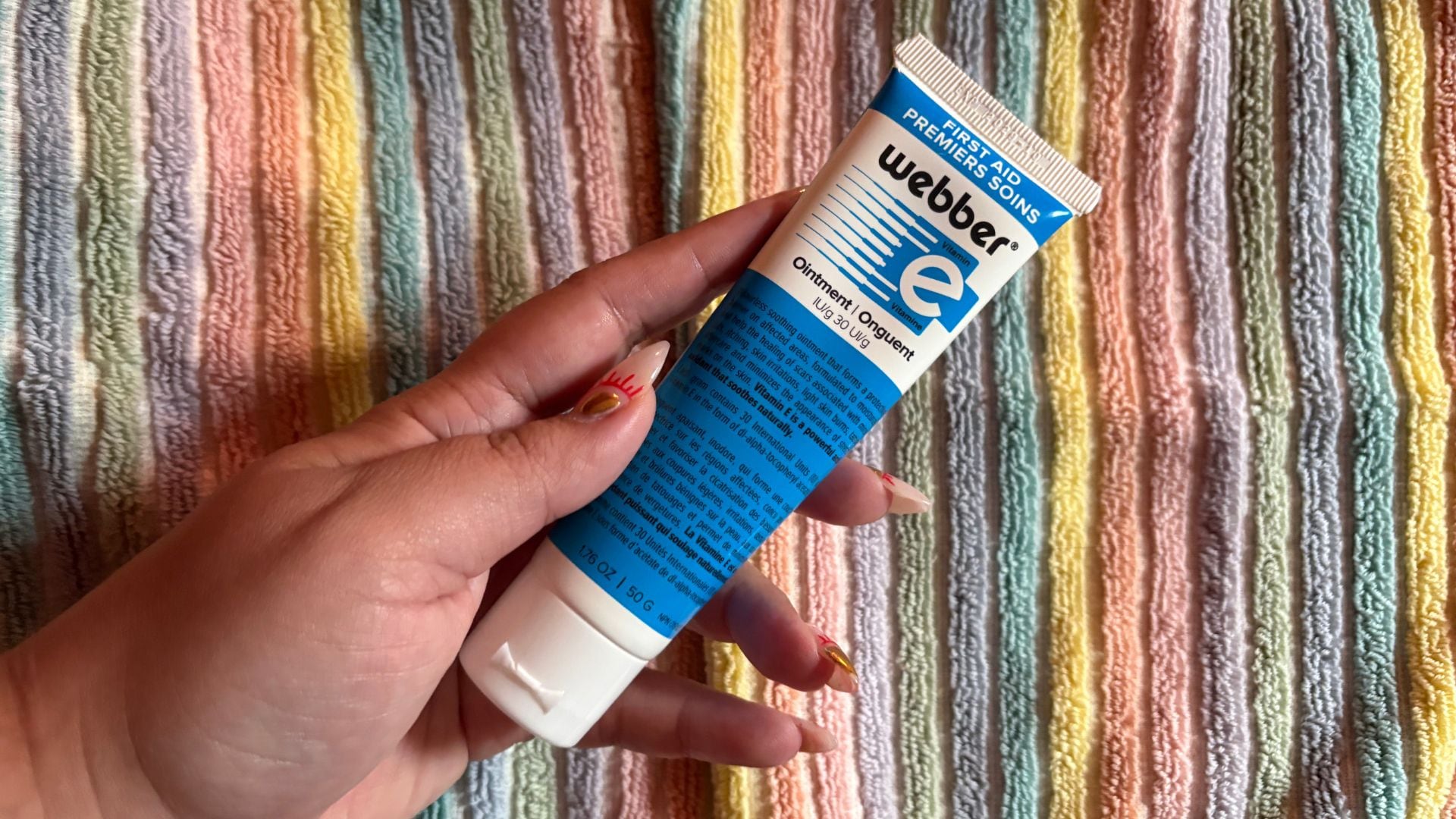 Bianca holding the tube of ointment over a colourful towel