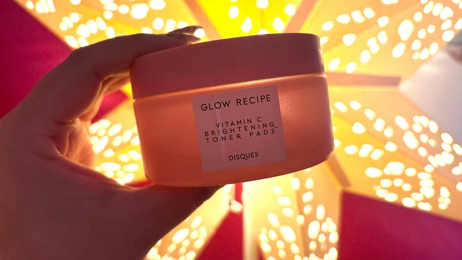 Bianca holding up the tub of toner pads with a light behind it