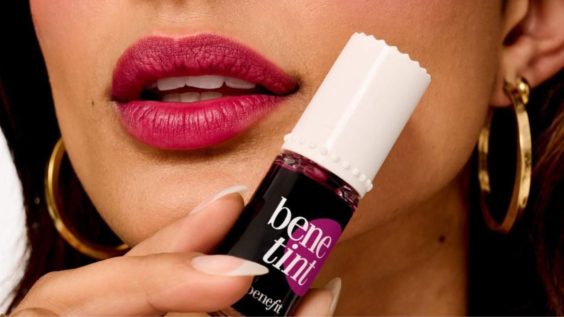 A person holding a bottle of Benetint next to their lips.