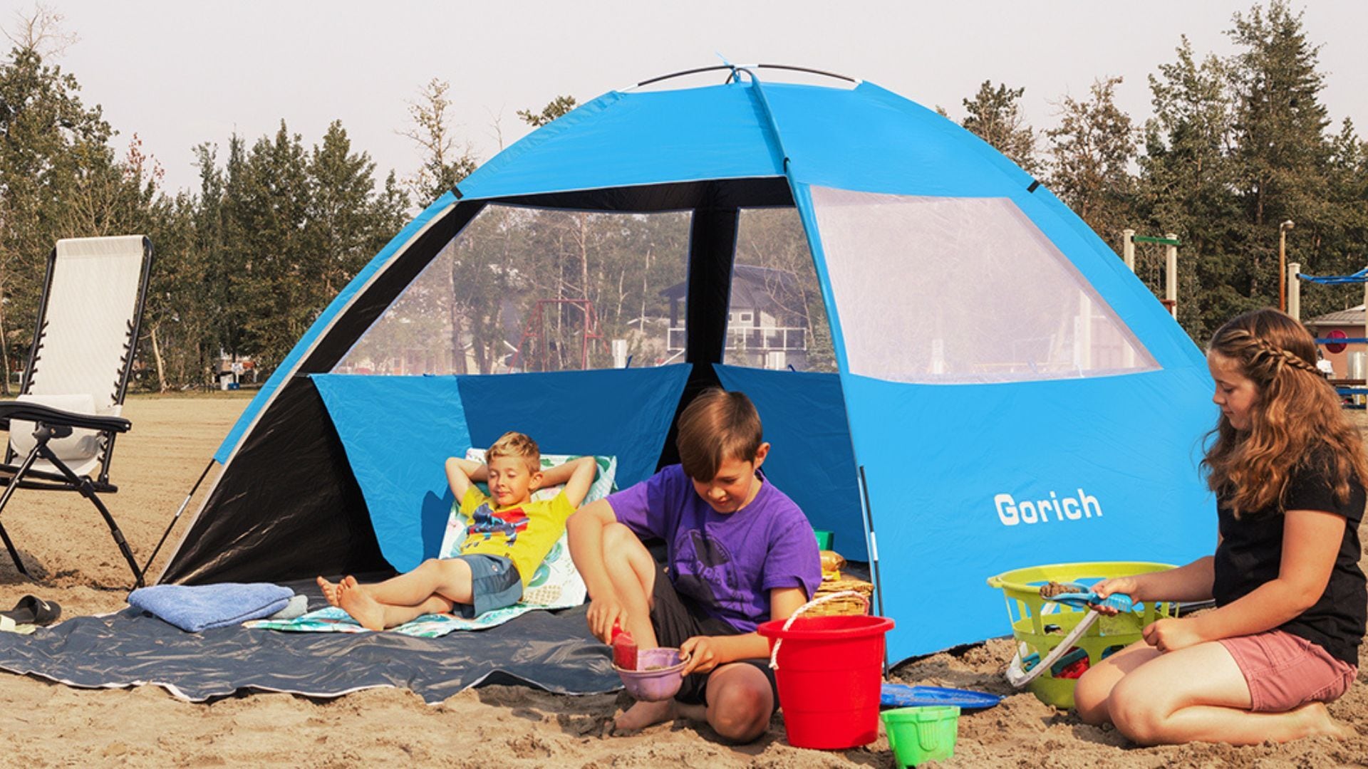 a family sitting under a beach tent on a beach