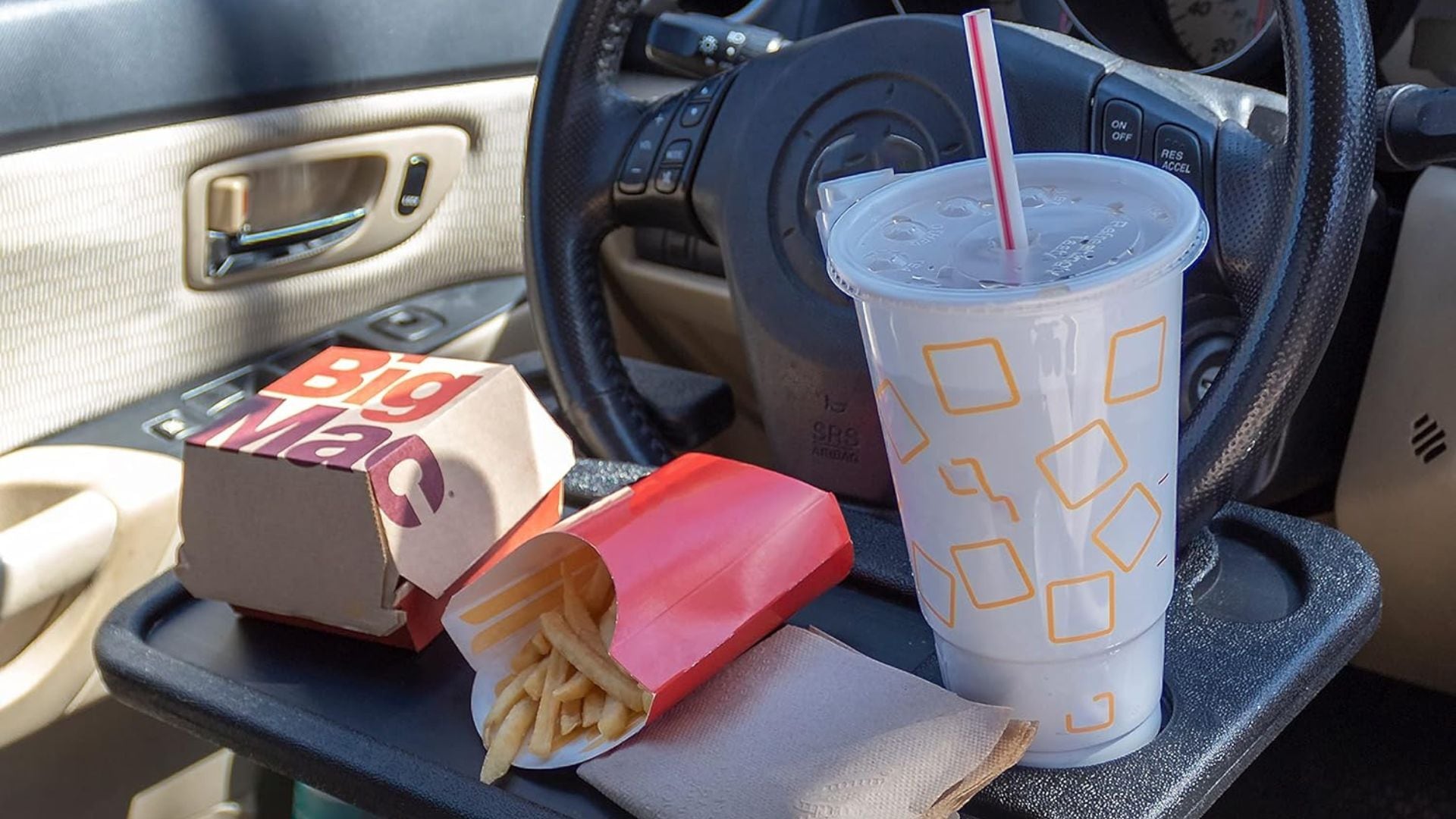 a car tray on a steering wheel with a fast food meal on it