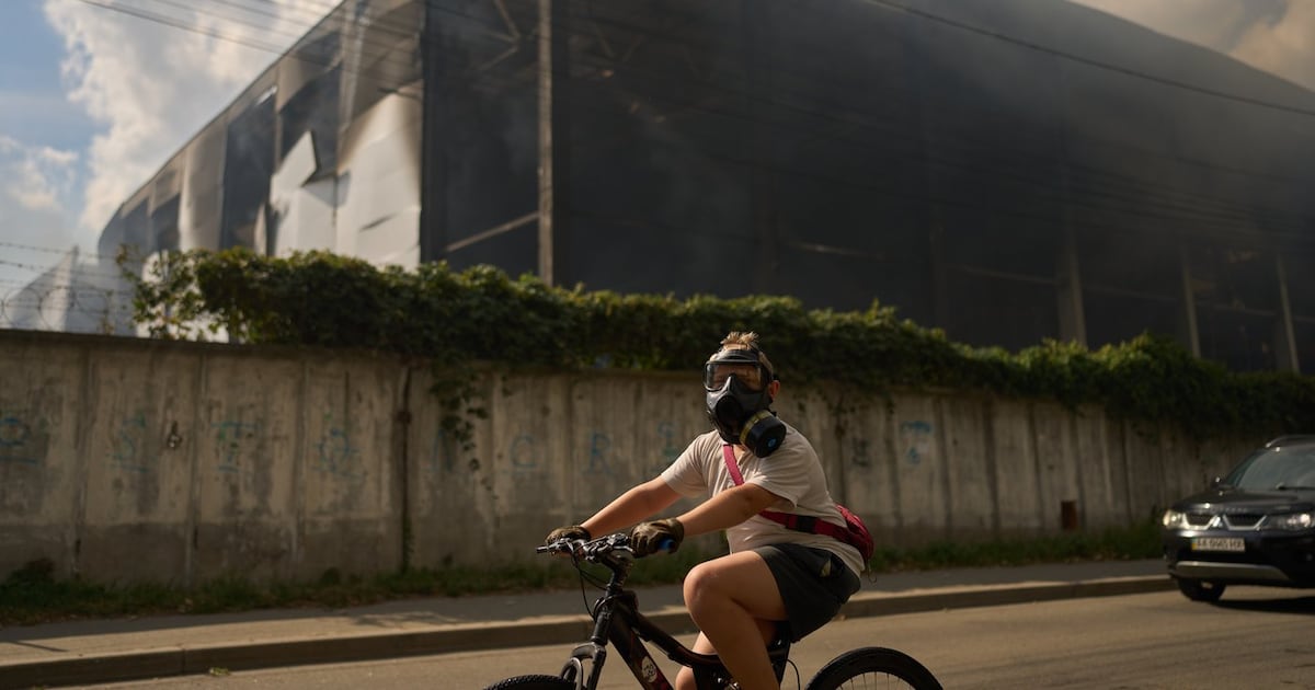 A local resident wears a gas mask as he rides a bicycle past a partially destroyed warehouse after a Russian drone attack in Brovary on the outskirts of Kyiv, Ukraine, Friday, Sept. 4, 2026. (AP Photo/Francisco Seco)
