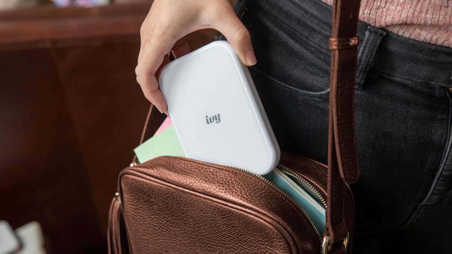 A person tucking an Ivy Smartphone Printer into their bag.