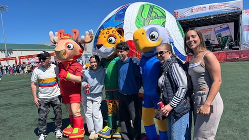 Soccer fans pose with mascots and a giant soccer ball.