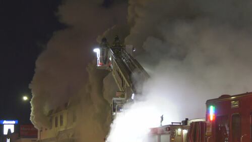 Firefighters on a ladder truck spray water on the old Jasper Place Hotel along Stony Plain Road in Edmonton the early morning of Feb. 19, 2026. (Sean McClune / CTV News Edmonton)