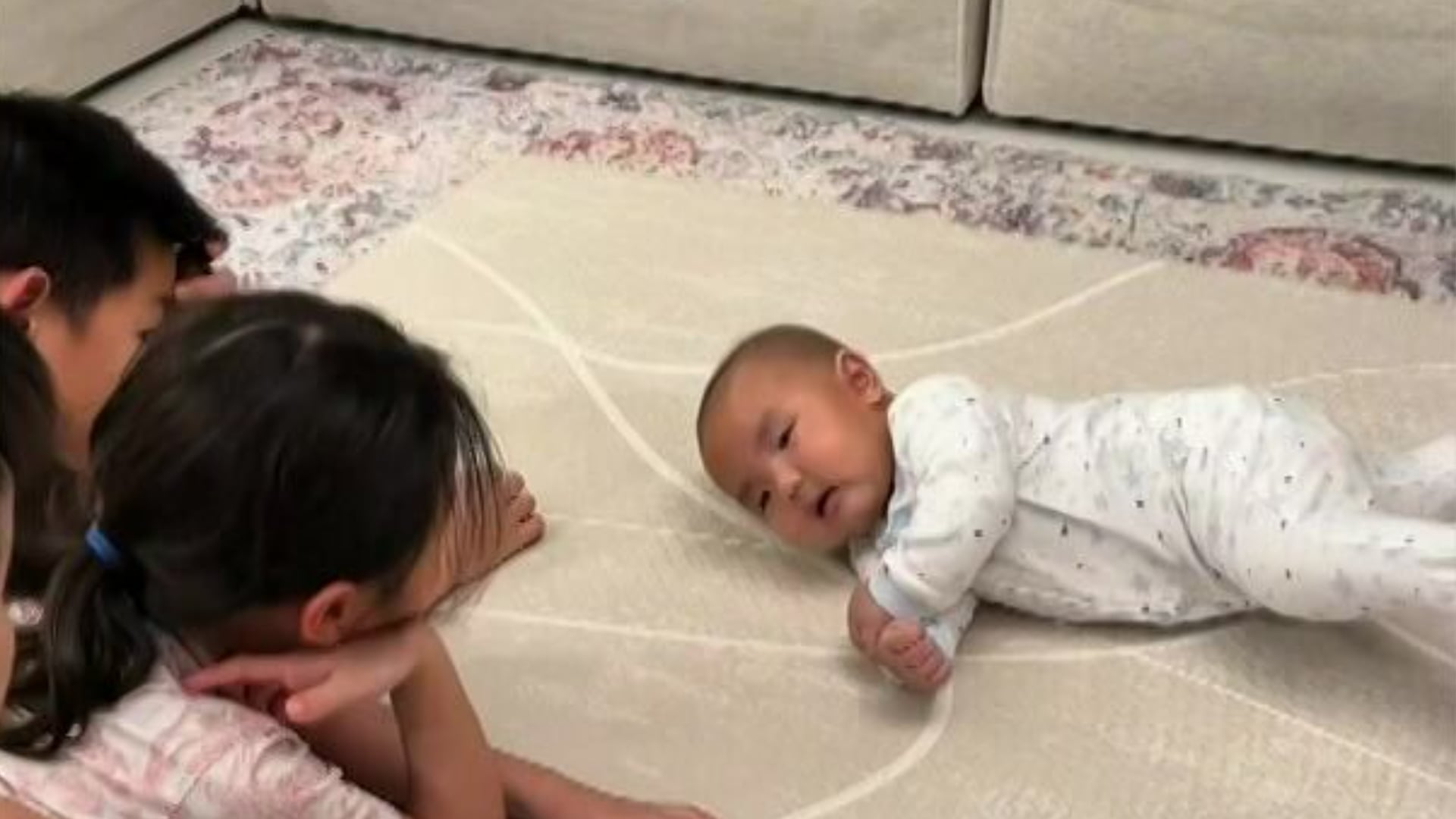 Siblings cheer on their baby brother for achieving his first rollover